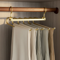 Clothing rack with gold hooks holding beige pants against a wooden background