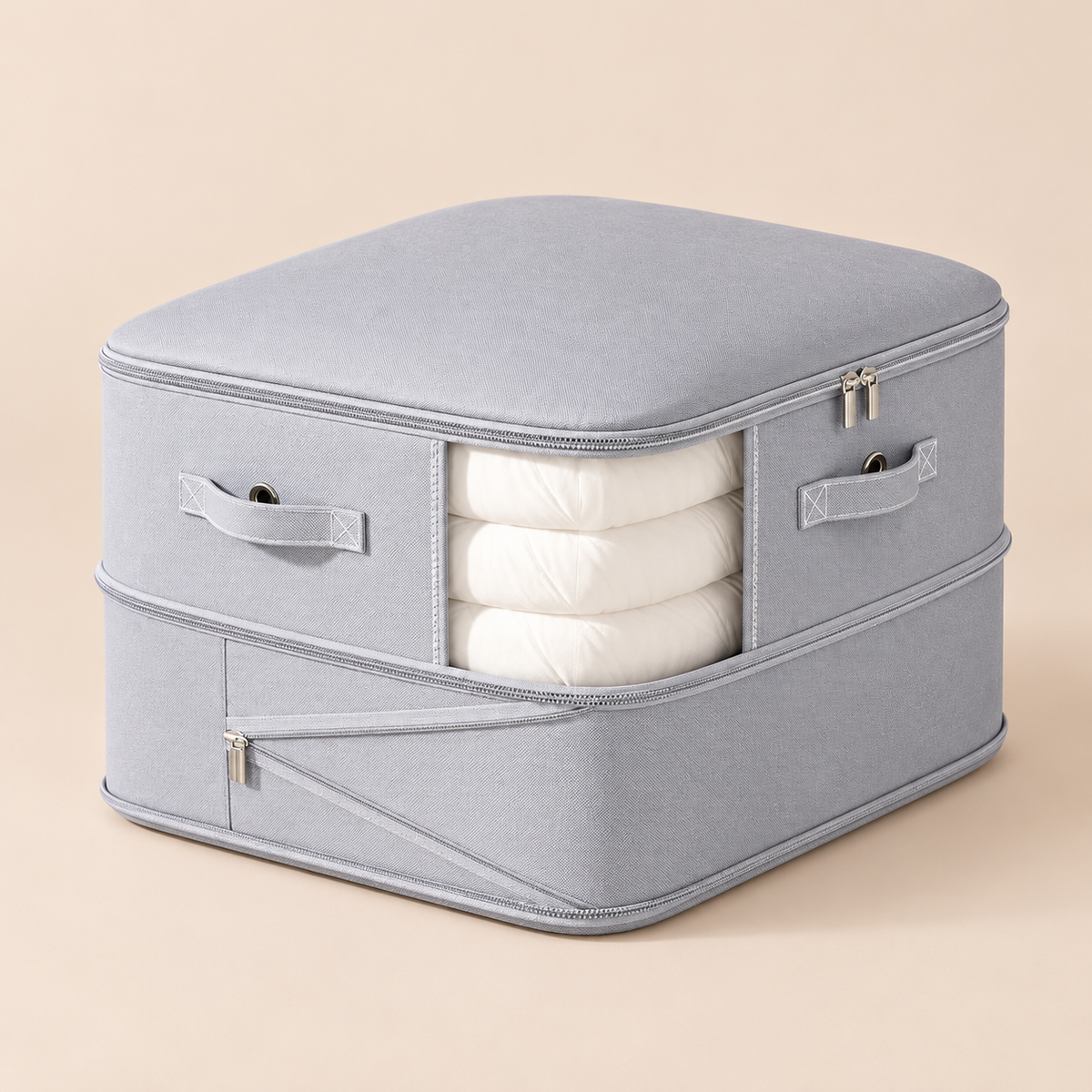 A light gray fabric storage bag with a zippered top and side pockets, shown holding three folded white sheets or blankets. The bag has fabric handles and silver zipper pulls, photographed on a plain beige studio background.