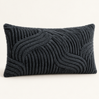 A rectangular lumbar throw pillow in a dark charcoal gray bouclé fabric with a raised wavy geometric pattern, shown against a plain off-white background.