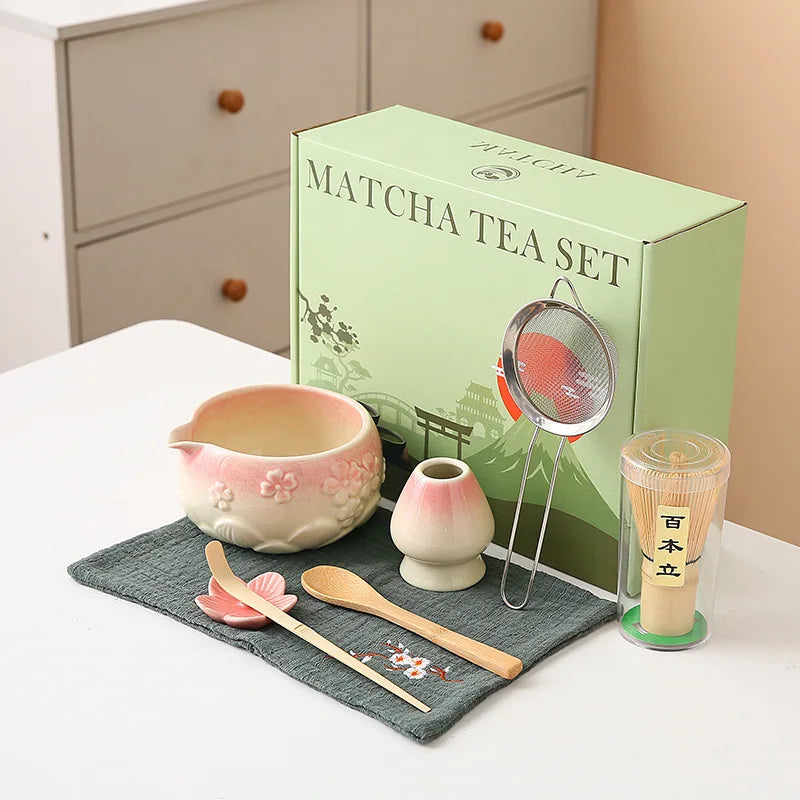 Ceramic matcha bowl set featuring a delicate cherry blossom design, complete with a bamboo whisk. The set showcases soft pink and white hues, perfect for 12