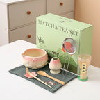 Ceramic matcha bowl set featuring a delicate cherry blossom design, complete with a bamboo whisk. The set showcases soft pink and white hues, perfect for 12