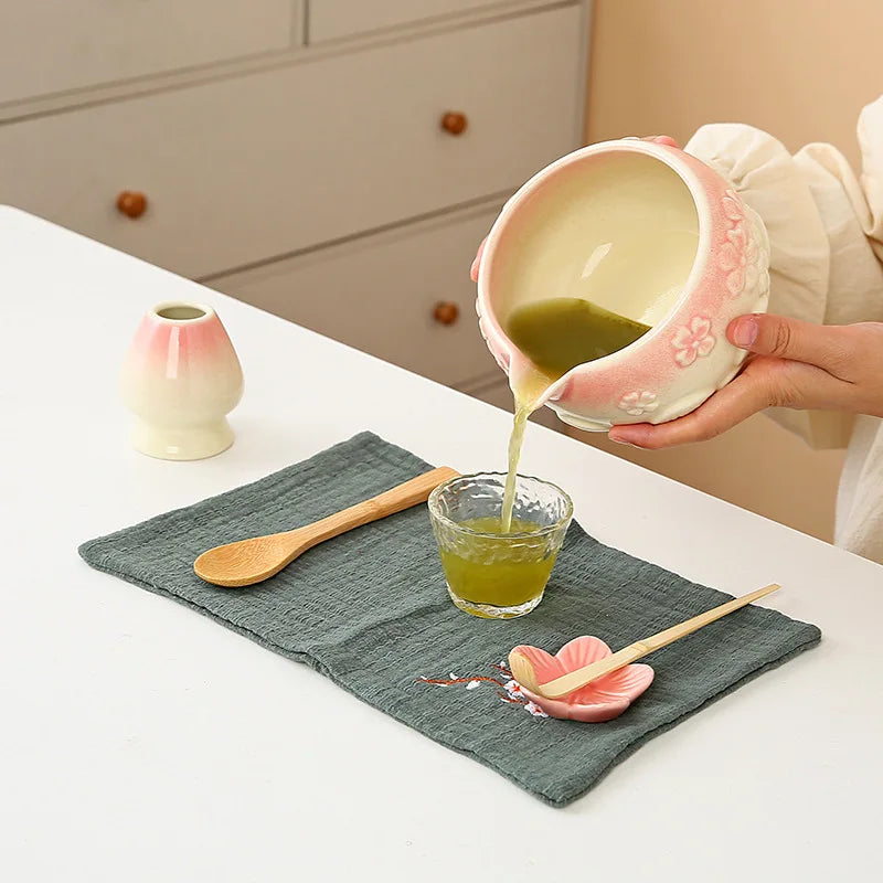 Ceramic matcha bowl set featuring a delicate cherry blossom design, complete with a bamboo whisk. The set showcases soft pink and white hues, perfect for 2