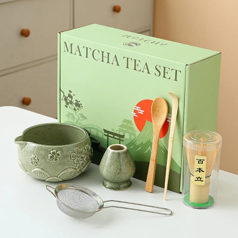 Ceramic matcha bowl set featuring a delicate cherry blossom design, complete with a bamboo whisk. The set showcases soft pink and white hues, perfect for 21