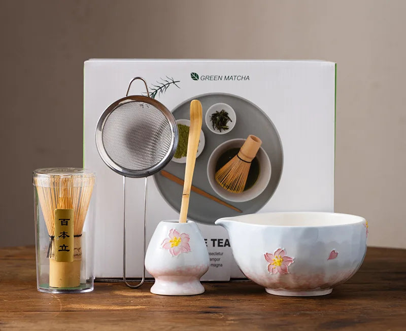 Elegant 5-piece ceramic matcha tea set featuring a delicate cherry blossom design. Includes a matcha bowl, whisk, scoop, and two cups. 5
