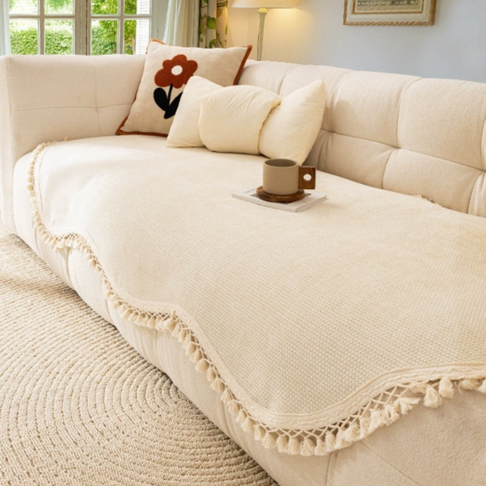 Elegant chenille woven sofa cover in a soft cream color, featuring decorative tassels at the edges. This stylish slipcover adds texture and sophistication to your 0