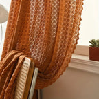 Earthy orange crochet curtain made from a soft microfiber blend, featuring a boho chic design. Measures 52 x 84 inches, perfect for adding 1