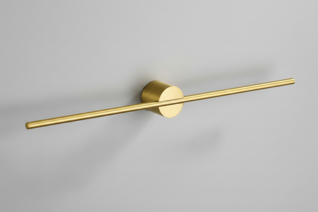 Gold wall-mounted light fixture on a pink background
