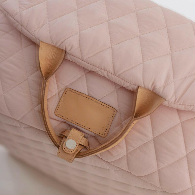 Beige quilted fabric pet carrier that doubles as a car seat. Features padded sides for comfort, sturdy exterior, and adjustable straps. Compact size of 7