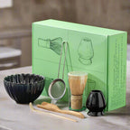 A set of traditional Japanese matcha tea preparation tools displayed in front of their packaging box, including a blue matcha bowl, a bamboo whisk, a bamboo rest, a metal sifting bowl, and two small blue cups.