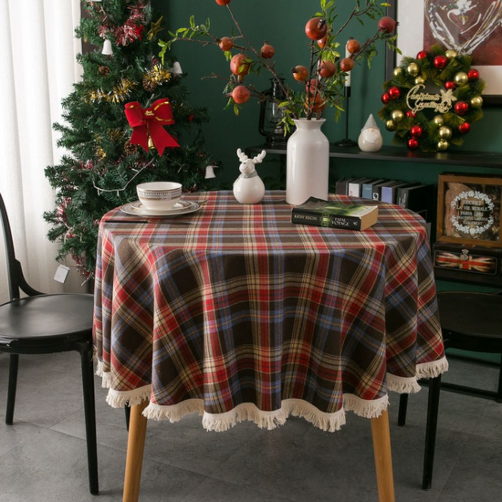 Round tablecloth featuring a vintage holiday plaid pattern in red, green, and white, adorned with decorative tassels. Made from durable fabric, perfect for 5