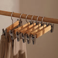 Set of wooden pants hangers featuring sturdy clips for secure grip, designed for closet organization. Natural wood finish complements any decor, providing an elegant touch while 0