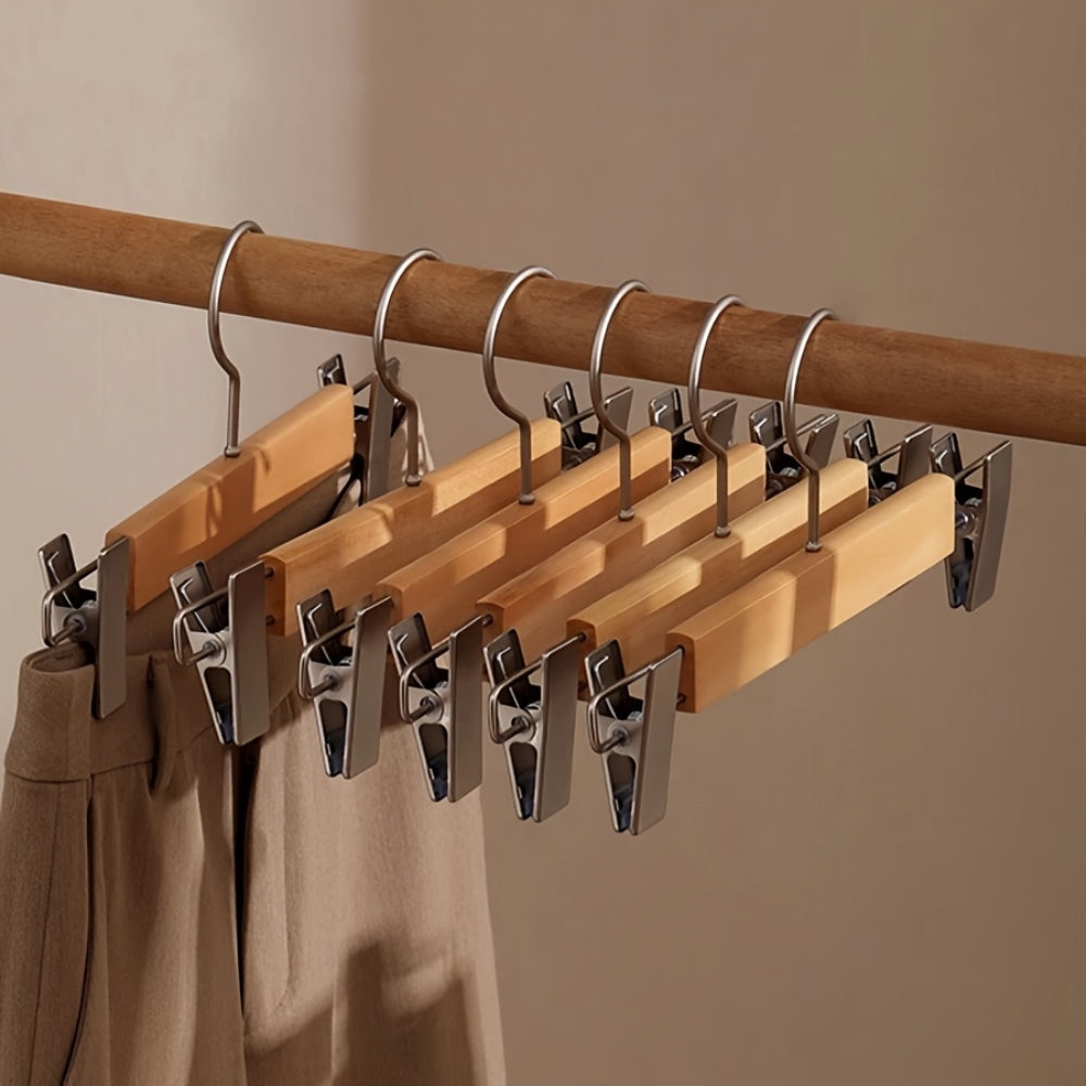 Set of wooden pants hangers featuring sturdy clips for secure grip, designed for closet organization. Natural wood finish complements any decor, providing an elegant touch while 0