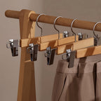 Set of wooden pants hangers with adjustable clips, designed for closet organization. The natural wood finish adds elegance, while sturdy clips securely hold trousers. Ideal 1