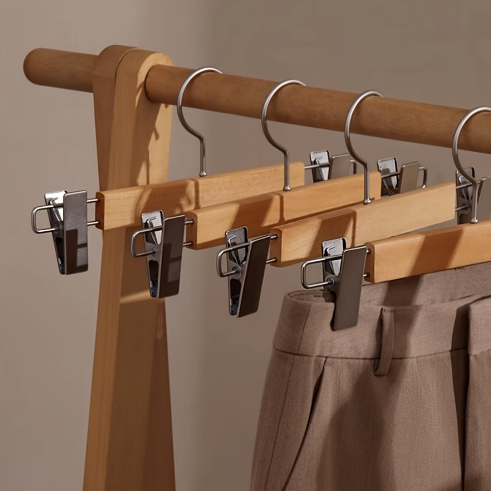 Set of wooden pants hangers with adjustable clips, designed for closet organization. The natural wood finish adds elegance, while sturdy clips securely hold trousers. Ideal 1