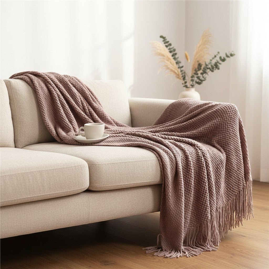 Dear Hazel taupe knit blanket with fringe detail draped over a cream sofa, featuring a Scandinavian design.